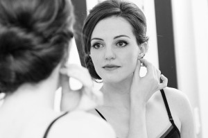 Woman_wearing_earring_in_front_of_mirror